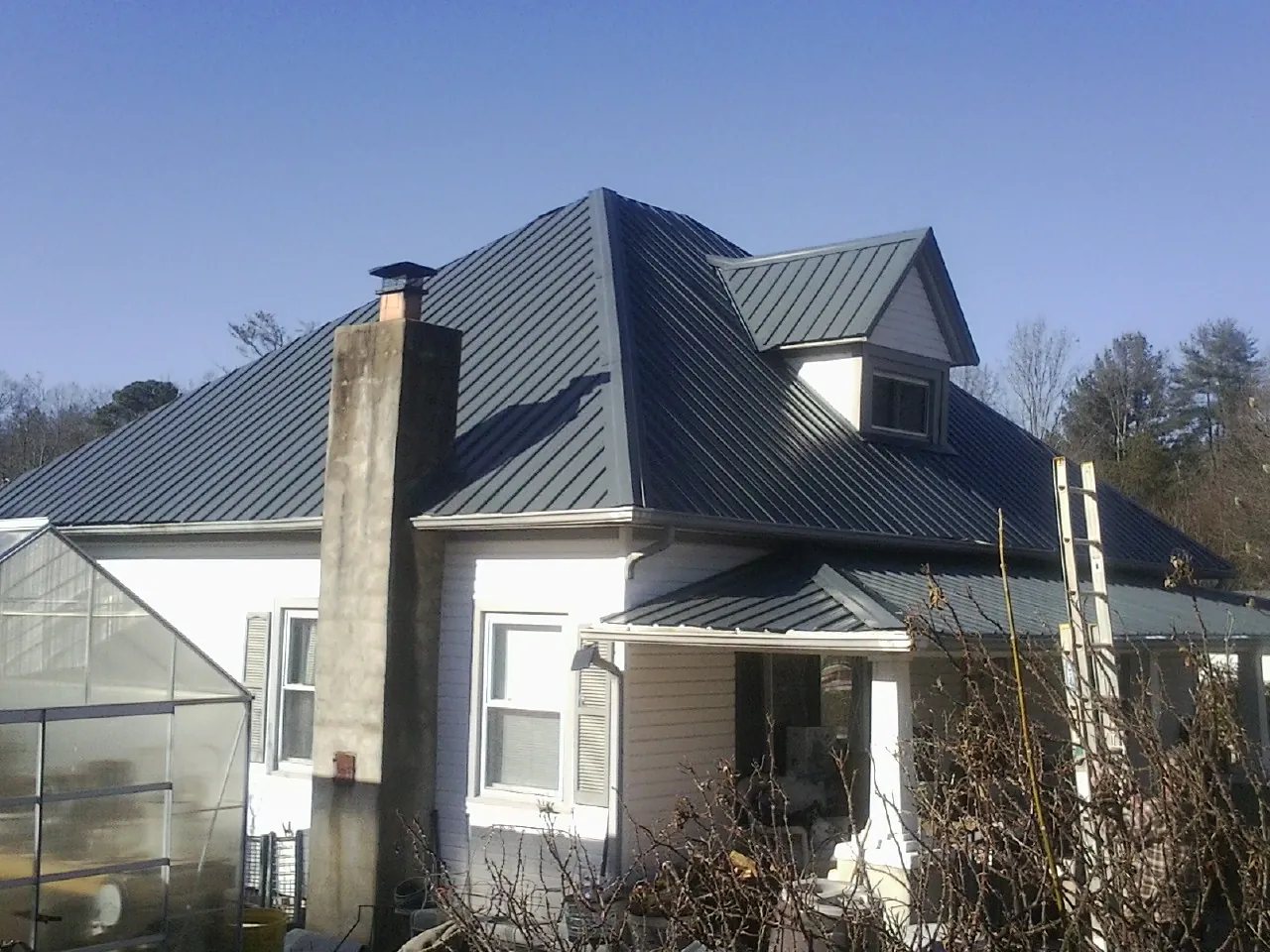 Dark blue standing seam metal roof on a white farmhouse with dormer — Slate & Tile Roof Repair by Roofing Brothers in Carnegie