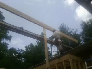 Carpenter setting a ridge beam over a new addition frame — Ice Dam Removal by Roofing Brothers in Carnegie