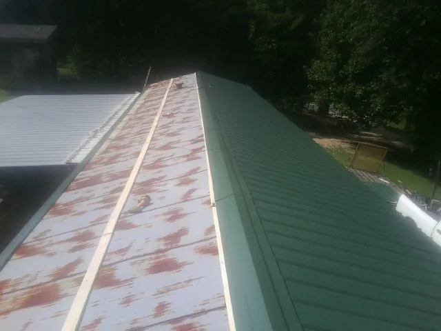 Old rusted panels beside newly installed green metal roofing — Wind Damage Roof Repair by Roofing Brothers in Carnegie