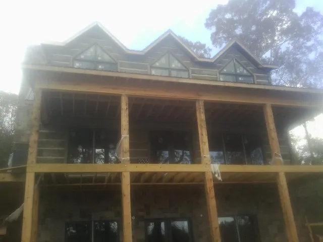 Dormers and porch framing on a large log home under construction — Roof Coating work by our crew in Carnegie