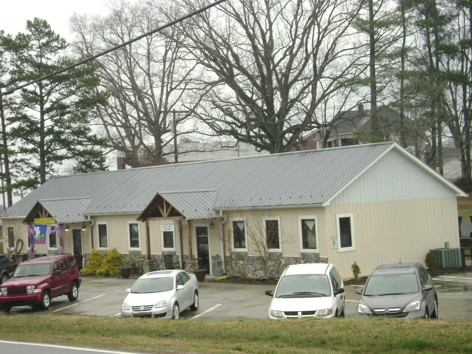 Gray metal roof with timber entry brackets on a small commercial building in Carnegie