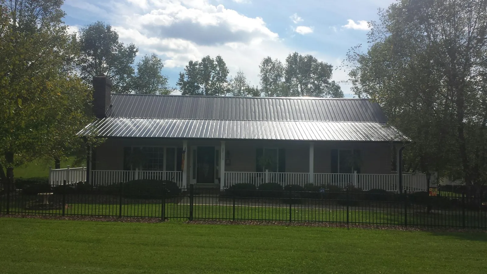 Gray metal roof on a brick ranch with a full width front porch — Gutter Guard Installation work by our crew in Carnegie