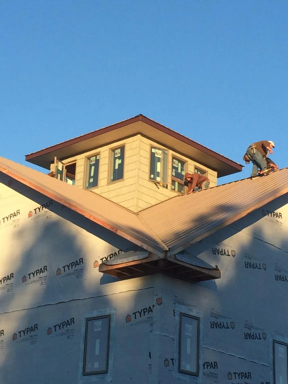 Roofers working around a rooftop cupola on a new metal roof at sunset — Roof Waterproofing in Carnegie by Roofing Brothers